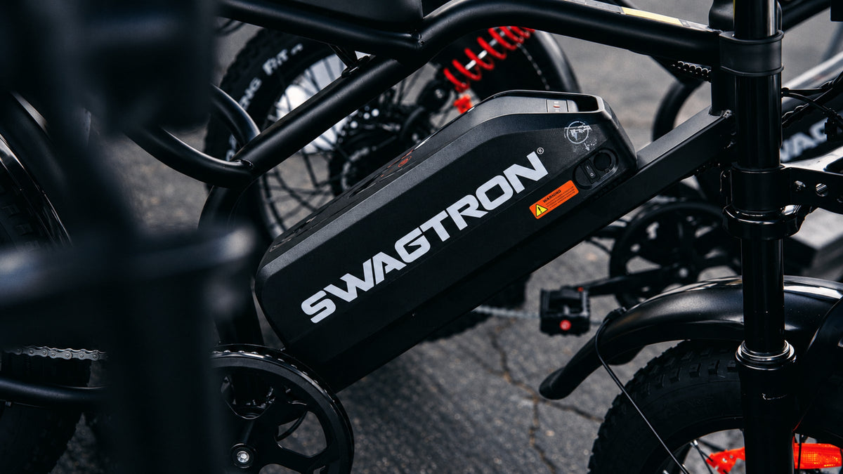 Close-up of the SWAGTRON battery pack mounted on an UrbanCruise e-bike frame, with the red rear shock behind it