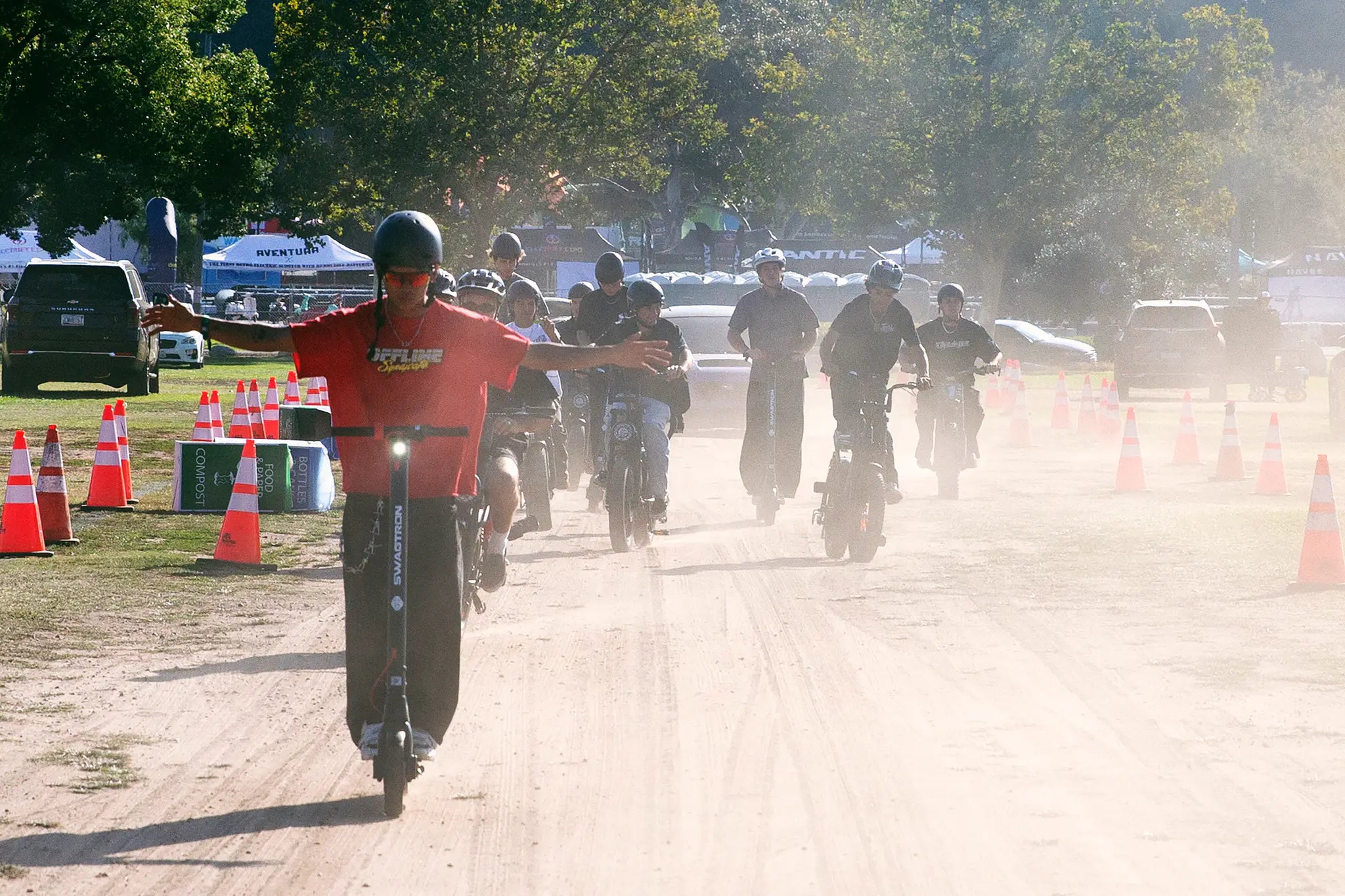 Riders on SWAGTRON scooters and e-bikes roll out through the dust on the Demo Days course.